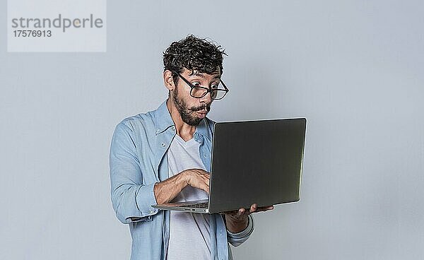 Gut aussehender Mann seinen Laptop isoliert  überrascht Mann seinen Laptop zu überprüfen  Kerl mit Laptop