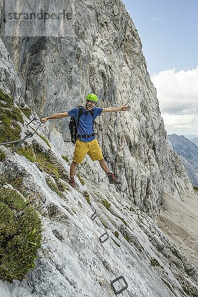 Junger Mann streckt Arme und beine aus  klettert im Klettersteig  Wanderweg zur Lamsenspitze  Karwendelgebirge  Alpenpark Karwendel  Tirol  Österreich  Europa