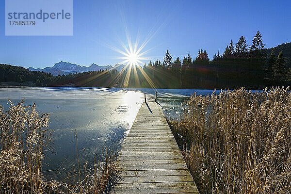 Holzsteg mit zugefrorenem See und Sonne  Geroldsee  Wagenbrüchsee  Gerold  Krün  Krun  Oberbayern  Bayern  Deutschland  Europa