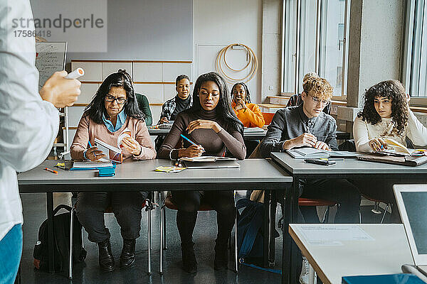 Multirassische Schüler sitzen am Schreibtisch und lernen vom Lehrer im Klassenzimmer