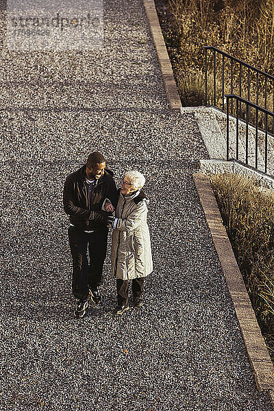 Hohe Winkel Ansicht der männlichen Krankenschwester zu Fuß mit älteren Frau im Park