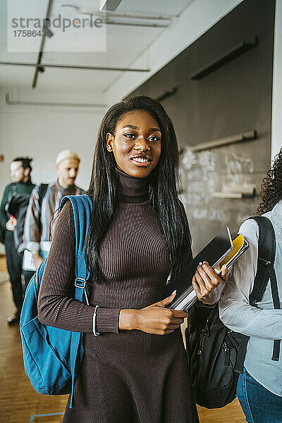 Porträt einer lächelnden jungen Frau  die mit einer Freundin an der Universität spazieren geht