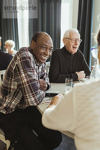Lächelnder älterer Mann im Gespräch mit einem Freund im Pflegeheim