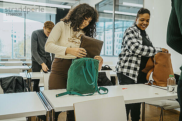 Multirassische Studenten packen Rucksack im Klassenzimmer des Community College