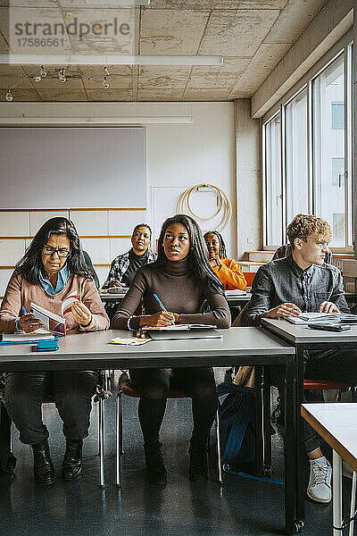 Multirassische Universitätsstudenten sitzen am Schreibtisch und lernen im Klassenzimmer