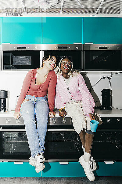 Glückliche junge Frauen sitzen am Küchentisch im Studentenwohnheim