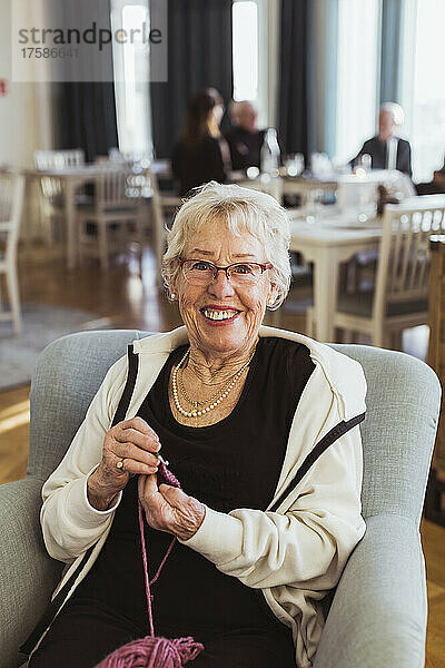 Porträt einer lächelnden älteren Frau  die im Pflegeheim strickt