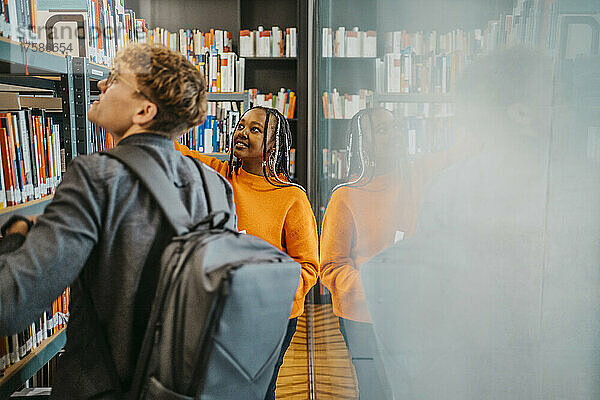 Junge Freunde suchen gemeinsam ein Buch in der Bibliothek der Universität