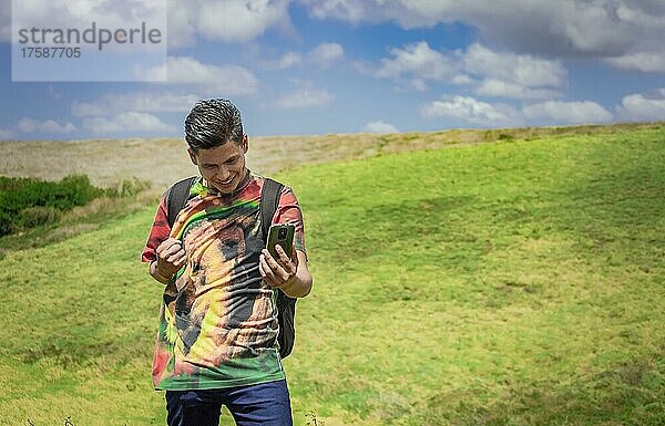Fröhlicher Mann beim Fotografieren im Feld  junger Mann beim Fotografieren im Feld mit seinem Handy