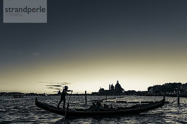 Gondoliere mit Gondel im Sonnenuntergang  Kirche Santa Maria della Salute im Hintergrund  Venedig  Venetien  Italien  Europa