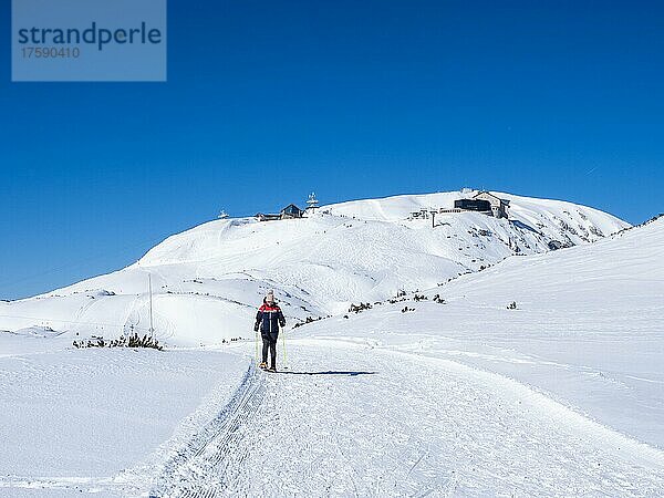 Blauer Himmel über Schneeschuhwanderin in Winterlandschaft  verschneite Berggipfel  Aussicht zum Krippenstein  Bergstation und Krippenstein Lodge  Salzkammergut  Oberösterreich  Österreich  Europa