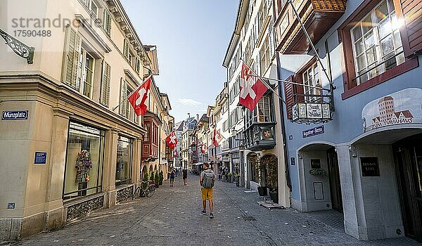 Tourist in der Augustinergasse  Straße mit historischen Häusern und Schweizer Flaggen in der Altstadt  Zürich  Schweiz  Europa