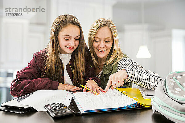 Mutter hilft Tochter (12-13) bei den Hausaufgaben am Schreibtisch