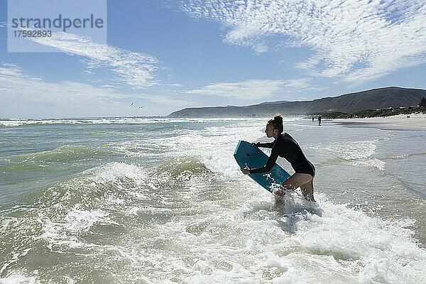 Mädchen (16–17) beim Surfen mit ihrem Bodyboard am Grotto Beach