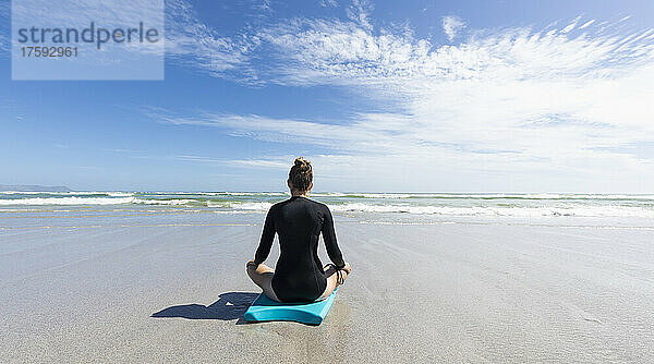 Mädchen (16-17) meditiert auf dem Bodyboard am Grotto Beach