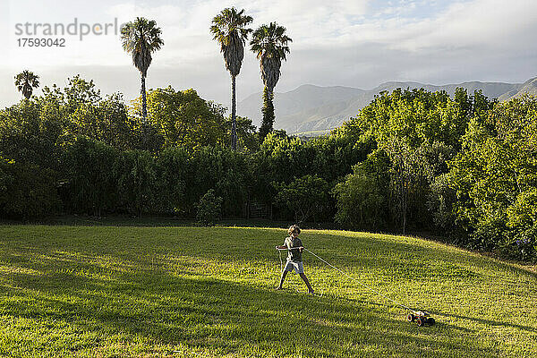 Südafrika  Stanford  Junge (8-9) zieht Spielzeugauto auf großer grüner Wiese