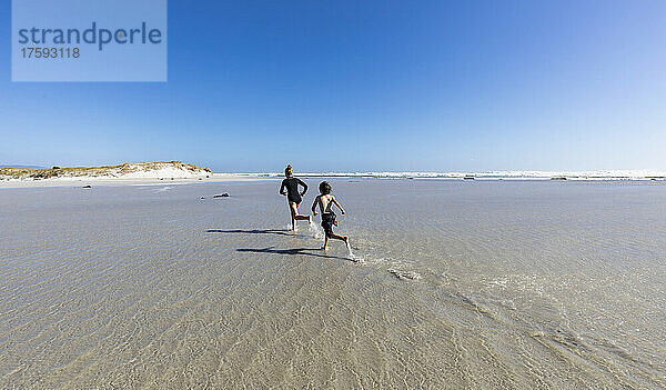 Südafrika  Hermanus  Mädchen (16-17) und Junge (8-9) laufen am Grotto Beach