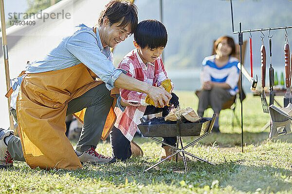 Japanisches Elternteil und Kind machen ein Feuer