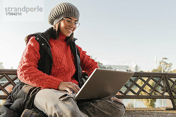Happy working woman using laptop at bench