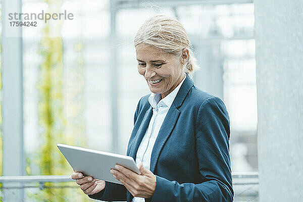 Happy businesswoman using tablet PC in office