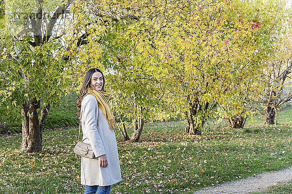 Lächelnde junge Frau verbringt ihre Freizeit im Herbstpark