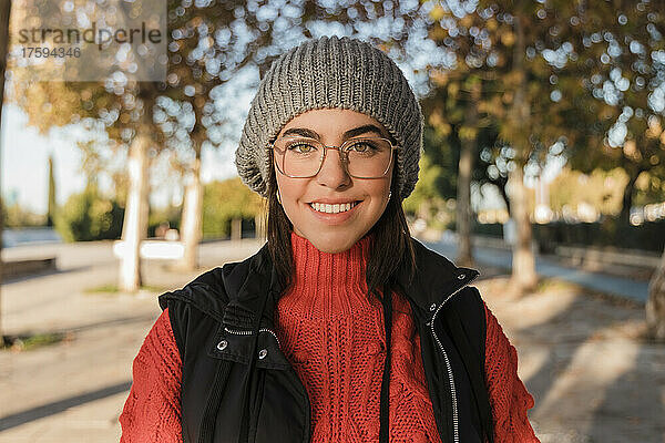 Glückliche junge Frau mit Strickmütze und Brille