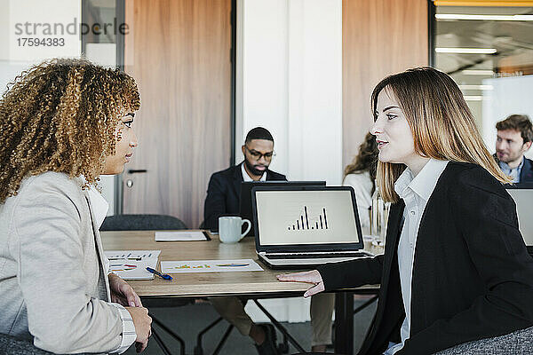 Junge Geschäftsfrau diskutiert mit Kollegen im Büro
