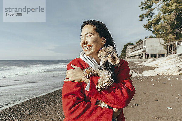 Glückliche Frau mit Yorkshire-Terrier am Strand