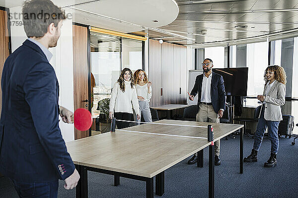 Geschäftskollegen spielen Tischtennis im Coworking-Büro