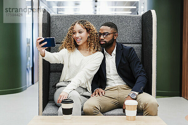 Geschäftskollegen machen ein Selfie  während sie in der Kaffeepause im Coworking-Büro sitzen