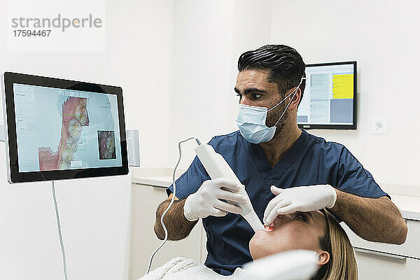 Zahnarzt analysiert die Zähne des Patienten auf dem Intraoralscanner-Bildschirm in der Klinik