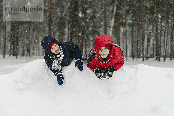 Glückliche Zwillingsbrüder spielen im verschneiten Wald