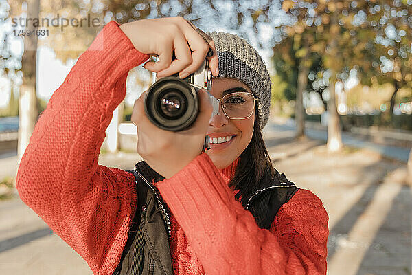 Smiling woman photographing through camera