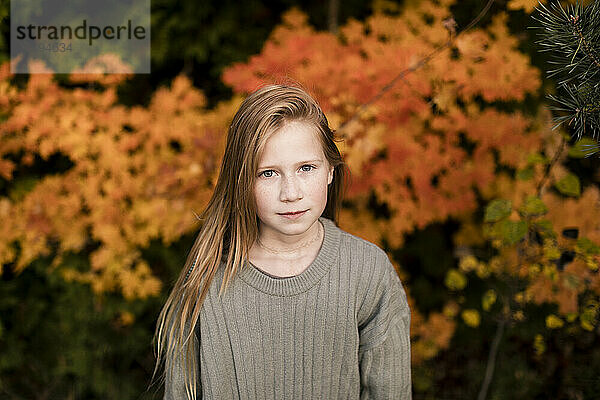 Young blond girl standing at autumn park