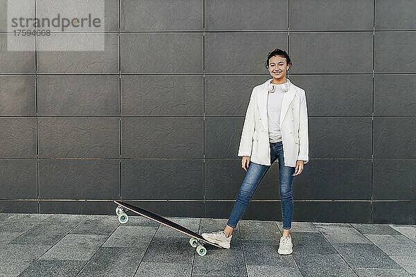 Lächelnde Frau mit Skateboard auf Fußweg