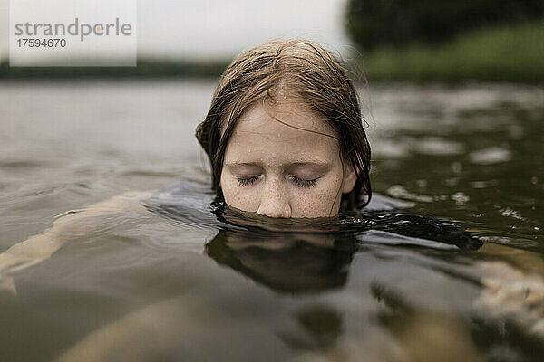 Mädchen mit geschlossenen Augen schwimmt im See