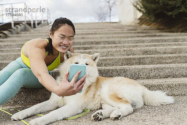 Smiling woman taking selfie with dog on smart phone