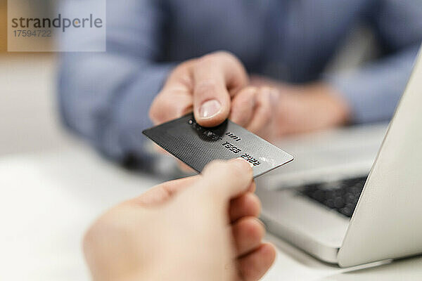 Kollegen halten Kreditkarte per Laptop im Büro