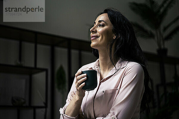 Lächelnde Geschäftsfrau beim Kaffee im Büro