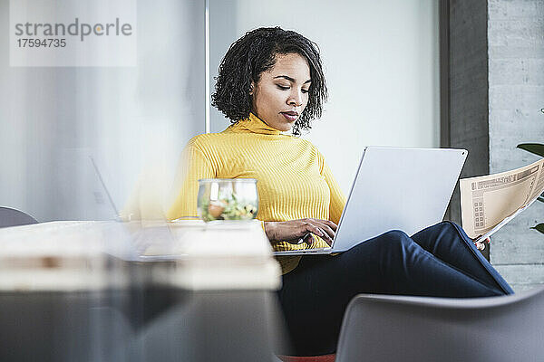 Junge Geschäftsfrau benutzt Laptop am Arbeitsplatz