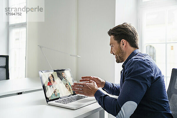 Geschäftsmann bespricht Ideen mit Kollegen per Videoanruf über Laptop im Büro