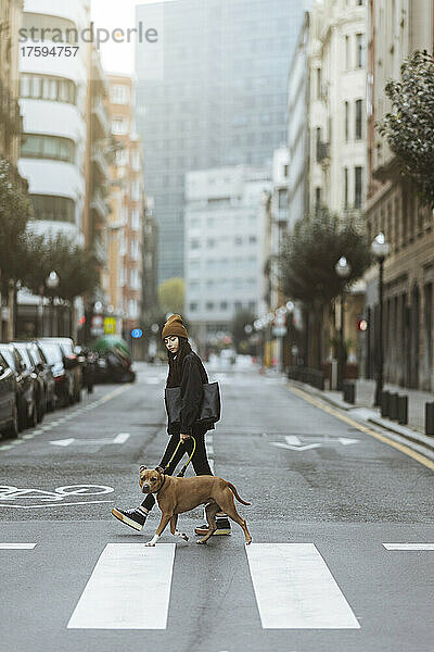 Junge Frau mit Hund überquert Straße in der Stadt
