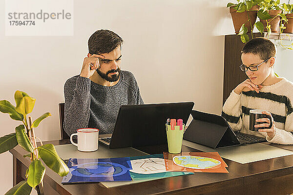 Kollegen nutzen Laptop und Tablet-PC am Schreibtisch in einem kleinen Büro