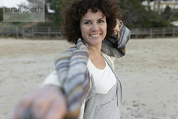 Lächelnde Frau steht auf Sand am Strand