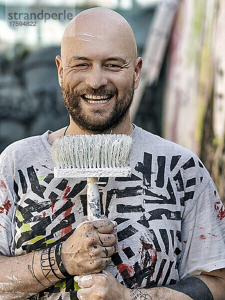 Smiling bald artist with paintbrush