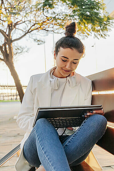 Frau benutzt Laptop auf Bank im Park