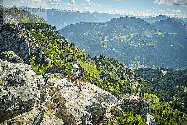 Junge klettert an einem sonnigen Tag auf Felsen