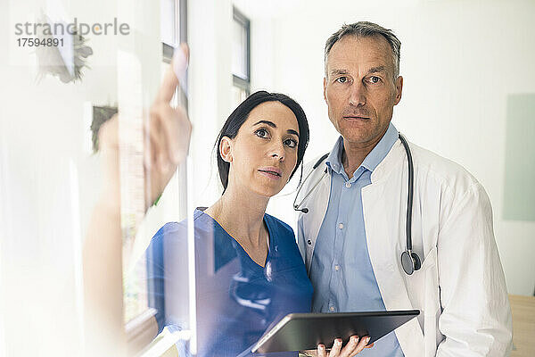 Krankenschwester hält Tablet-PC in der Hand und diskutiert mit Arzt im Krankenhaus