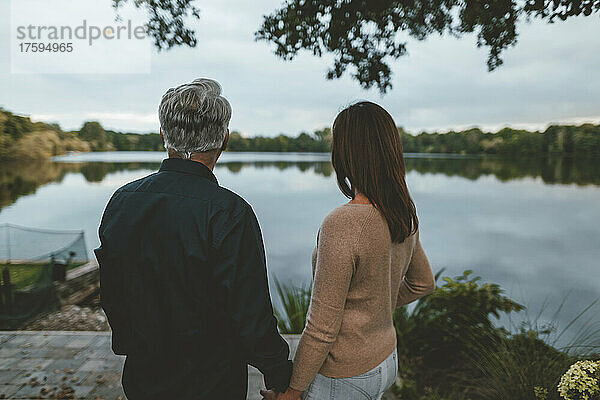 Paar hält Händchen und steht am See