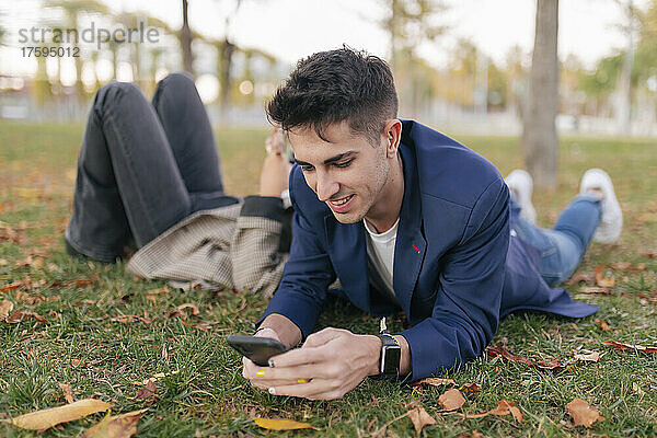 Geschäftsmann nutzt Smartphone und entspannt sich mit Kollegen im öffentlichen Park